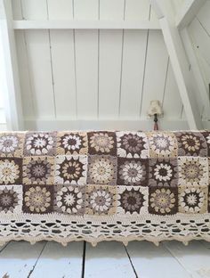 a crocheted bench cushion is sitting on the floor in front of a window