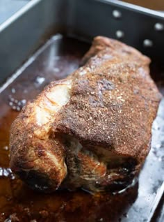 a piece of meat sitting on top of a pan covered in sauce and seasoning