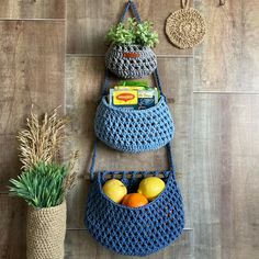 three crocheted purses hanging on the wall with fruits and vegetables in them