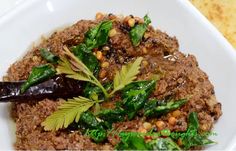 a white plate topped with meat covered in greens and spices on top of a table