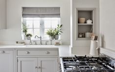 a kitchen with a stove top oven sitting next to a window filled with potted plants