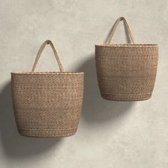 two woven baskets hanging on the wall, one is brown and the other is beige