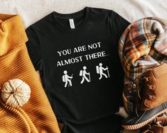 This funny hiking shirt makes a great addition to your wardrobe! Pair with other nature clothing to stand out from the crowd and embrace your sarcastic side. This also makes a great gift for anyone who loves camping, backpacking, hiking, and all things outdoors! You are not almost there t shirt.  ✳ Made to Order ✳ Pre-Shrunk ✳ Various Colors and Unisex Sizes ✳ Slim Fit ✳ Soft, High-Quality Fabric ✳ Please note: there may be a slight color variation due to lighting and different screen settings ✳ If you need a different color or size, please reach out and I'll see what I can do for you!  Sizing ✳ Please check the listing photos for sizing to ensure you understand the length and width ✳ If you are unsure, measure a comparable piece from your wardrobe Care Instructions ✳ Cold Wash ✳ Tumble dr Funny Hiking Shirts, Funny Letter Print T-shirt For Outdoor, Funny Text Short Sleeve T-shirt For Outdoor, Black Pre-shrunk Shirt For Outdoor Activities, Black Hiking T-shirt With Letter Print, Black Letter Print T-shirt For Hiking, Fall Hiking T-shirt With Graphic Print, Black T-shirt For Hiking With Letter Print, Casual Outdoor T-shirt With Funny Text