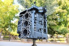 a large engine block sitting on top of a metal stand in the middle of a park