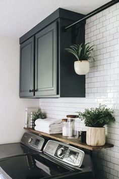 a washer and dryer in a room with white tiles on the walls, black cabinets