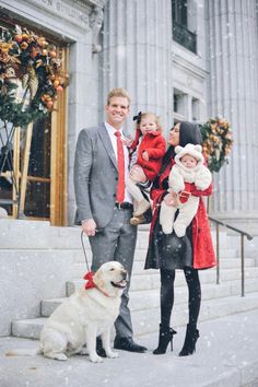 a man, woman and child standing on steps in the snow with a dog