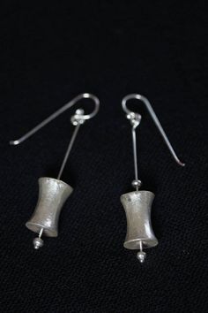 These earrings are composed of small silver beads and a bobbin-shaped hollow handmade silver piece, a design typical of Karen hill tribe people from northern Thailand. It is modernized into this simple composition, with the bobbin piece attached to a slender silver stem. It is crafted in 98% Silver, while the hook is in sterling silver. Our products are hand crafted in 98% Silver by Thai Karen hill-tribe artisans by means of traditional tools and techniques. The Karen are a group of ethnic peopl Silver Linear Earrings With French Hook Gift, Elegant Silver Linear Earrings With French Hook, Handmade Modern Silver Plug Earrings, Modern Handmade Silver Plug Earrings, Sterling Silver French Hook Drop Earrings, Silver Minimalist Dangle Plug Earrings, Unique Silver Jewelry With French Hook, Silver French Hook Earrings For Jewelry Making, Handmade Minimalist Silver Plug Earrings