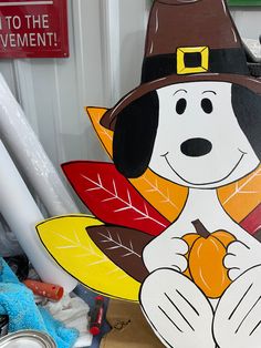 a wooden sign with a dog wearing a pilgrim's hat and holding an acorn