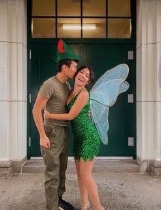 a man and woman dressed up as tinkerbells pose for a photo in front of a green door