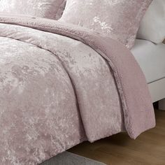 a bed with pink comforter and pillows on it