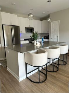 a kitchen island with four stools in front of it and a refrigerator freezer