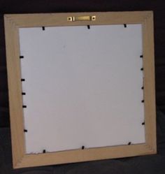 a wooden frame with holes in the middle and white paper taped to it, sitting on a black surface