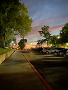 cars parked on the side of a road at night with trees in the foreground