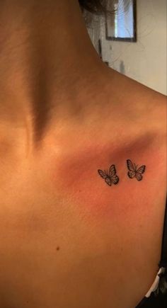 a woman's chest with two butterflies on the left side of her shoulder and an upper half