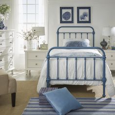 a blue metal bed frame in a bedroom with white walls and carpeted flooring