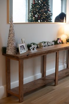 a wooden table with christmas decorations on it and a small tree in the corner behind it