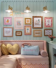 a pink couch with pillows and pictures on the wall