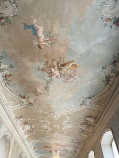 an ornate ceiling with paintings and chandeliers in a room that has white walls