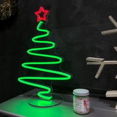 a green christmas tree with red and white stars on it next to a jar of paint