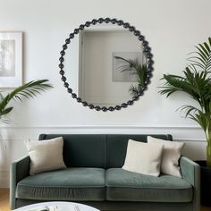 a living room with a green couch and two potted plants