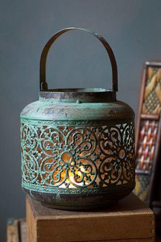 an ornate tea light holder sitting on top of a wooden box next to other items