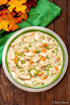 a bowl of chicken pot pie soup on a wooden table with autumn leaves and green napkin