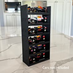 a display case filled with toy cars on top of a marble countertop in a kitchen