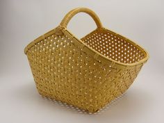 a woven basket is shown on a white surface with the handle extended to it's side