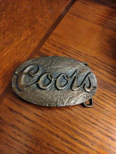 a close up of a metal object on a wooden table with the word coco's written in cursive writing