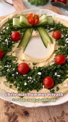 a hummus wreath with cucumbers and tomatoes on it