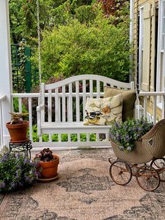 a white porch swing with potted plants on it and a baby carriage in the foreground