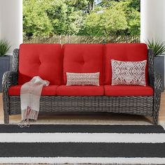 a red couch sitting on top of a wooden floor next to a white and black rug