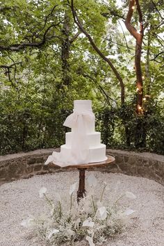 a wedding cake sitting on top of a wooden table in the middle of a forest