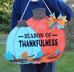 a person is holding a painted pumpkin sign