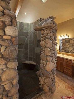 there is a stone shower in the bathroom with rocks on the walls and around it