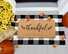 a welcome mat that says,'grateful'on it with fall leaves and pumpkins around it