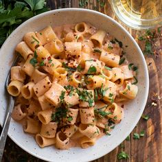 a white bowl filled with pasta and garnished with parsley