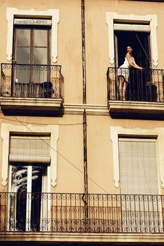 a woman standing on the balcony of an apartment building