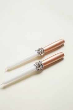 two white and rose gold - plated toothbrushes with crystals