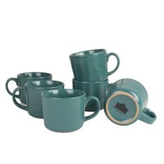 green coffee cups and saucers are stacked on top of each other in front of a white background