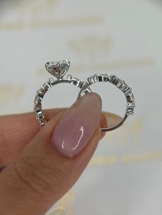 a person holding two rings with diamonds on them in their hand and the ring has been made out of silver