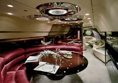 the interior of an airplane with red couches and round tables set up for formal function