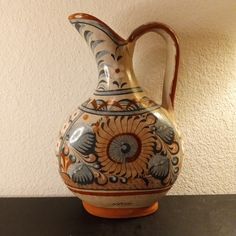 a vase sitting on top of a table next to a white wall and a black counter