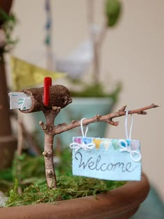 a welcome sign hanging from a tree branch with a small tag attached to it that says welcome