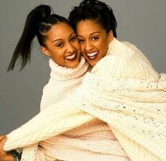 two women are hugging each other while wearing sweaters and scarves on their heads