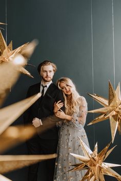 a man and woman standing next to each other in front of gold stars hanging from the ceiling