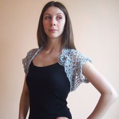 a woman is standing with her hands on her hips, wearing a black top and crocheted shawl