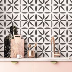 a kitchen with pink cabinets and black and white tiles on the wall, along with wooden utensils