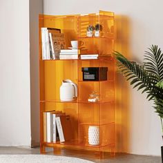 an orange shelving unit with books and plants