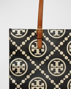 Tory Burch tote bag in T monogram embossed leather     Adjustable buckle shoulder straps, 10.2" drop    Open top with side snap closures     Interior, one zip pocket and one slip pocket     Lining: Nylon/polyurethane    Approx. 12.4"H x 15.8"W x 6"D    Imported Tory Burch Tote Bag, T Monogram, Tory Burch Tote, Tory Burch Bag Totes, Pennsylvania Dutch, Side Snap, Oversized Tote Bag, Womens Designer Handbags, Designer Totes